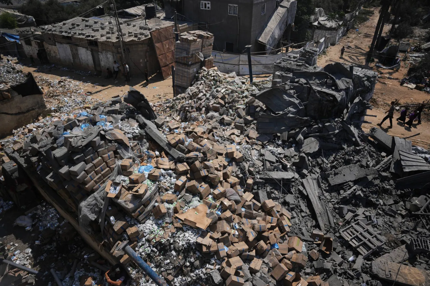  Palestinians walk past a food-aid warehouse damaged in an Israeli airstrike that targeted a nearby house in Deir al-Balah, central Gaza Strip, Wednesday, Aug. 26, 2026. (AP)