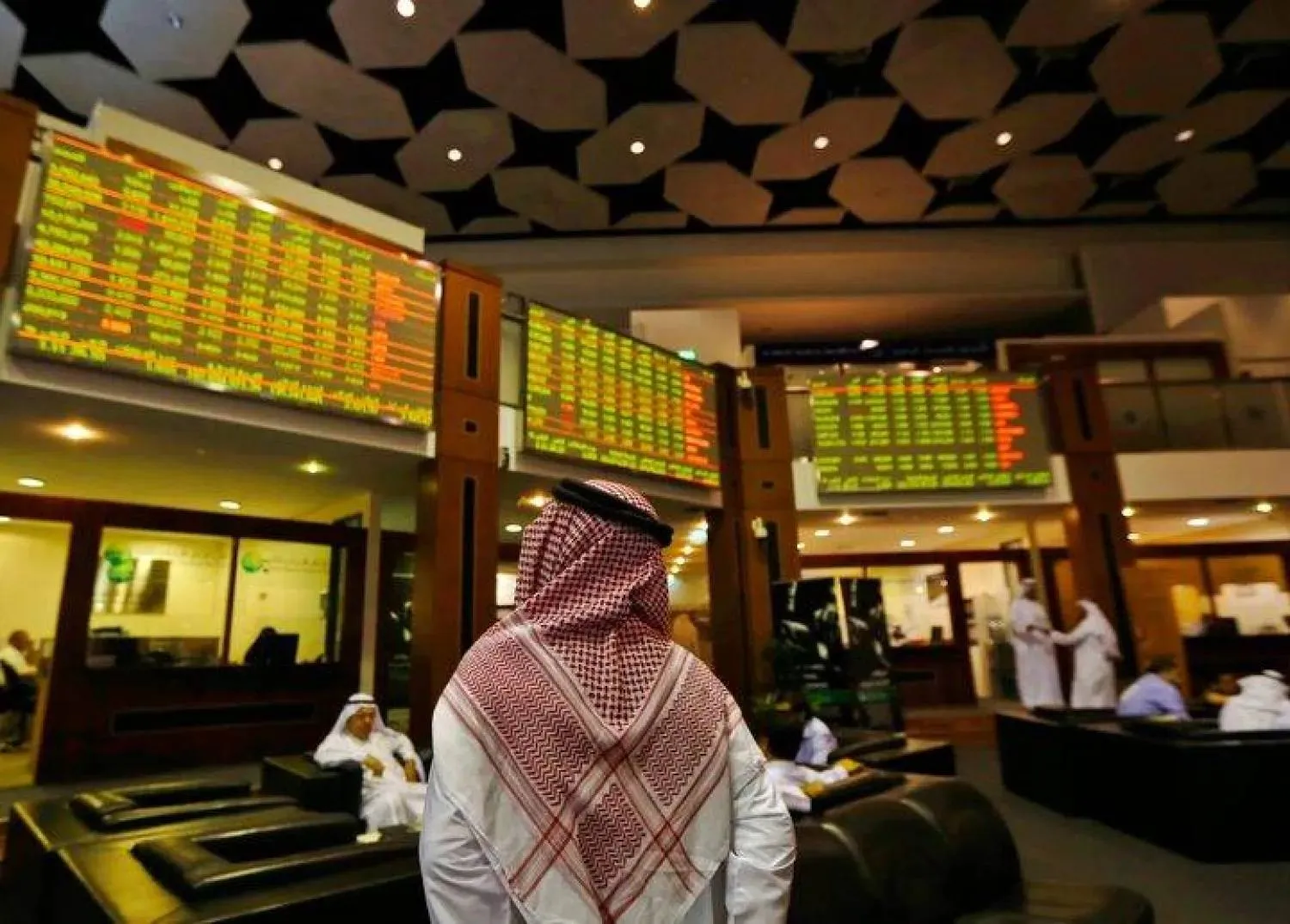 An investor looks up at screens displaying stock information at the Dubai Financial Market, June 17, 2013. REUTERS/Jumana El Heloueh/File Photo
