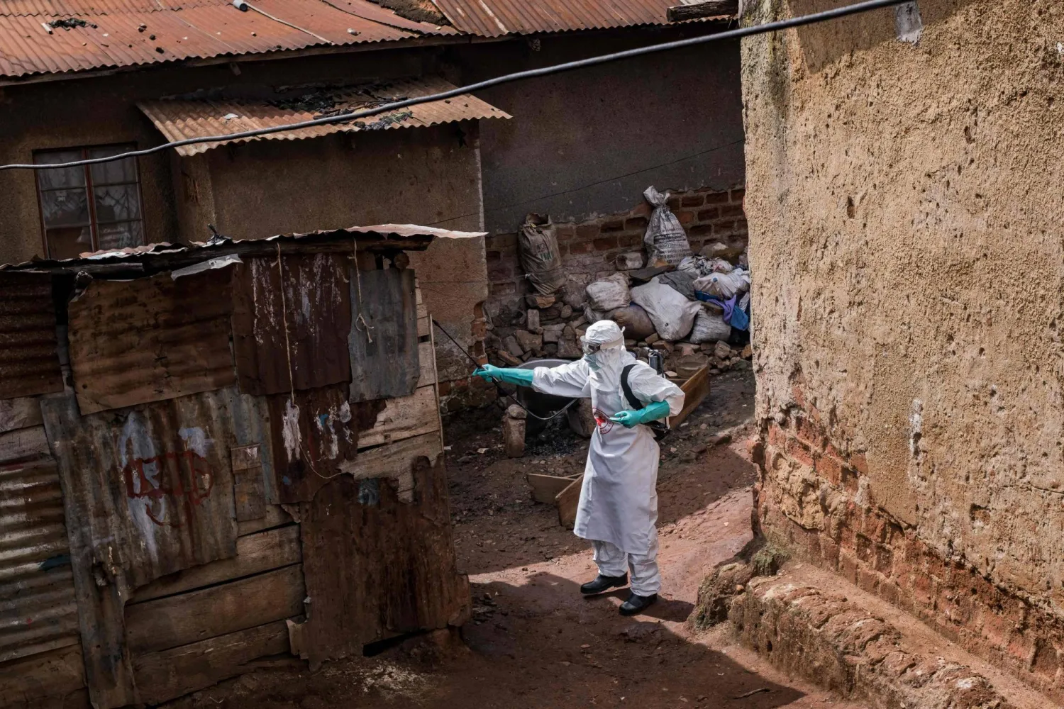 A Uganda Red Cross Society worker in protective gear sprays disinfectant at the home of a suspected Ebola victim in Kampala on May 26, 2026. (AFP)
