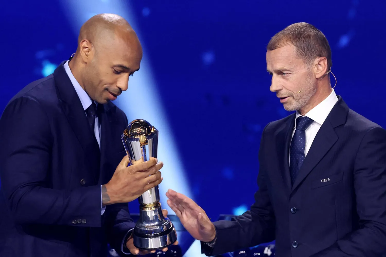 اللاعب الفرنسي السابق تييري هنري يتسلم جائزة من رئيس الاتحاد الأوروبي لكرة القدم «يويفا» ألكسندر تسيفيرين (أ.ف.ب)