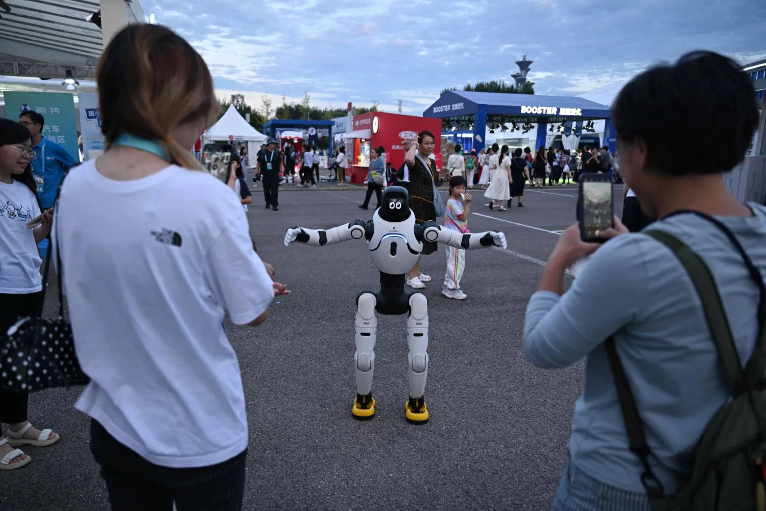 People interact with a humanoid robot outside the 2nd World Humanoid Robot Games at the National Speed Skating Oval in Beijing on August 26, 2026. (AFP) 