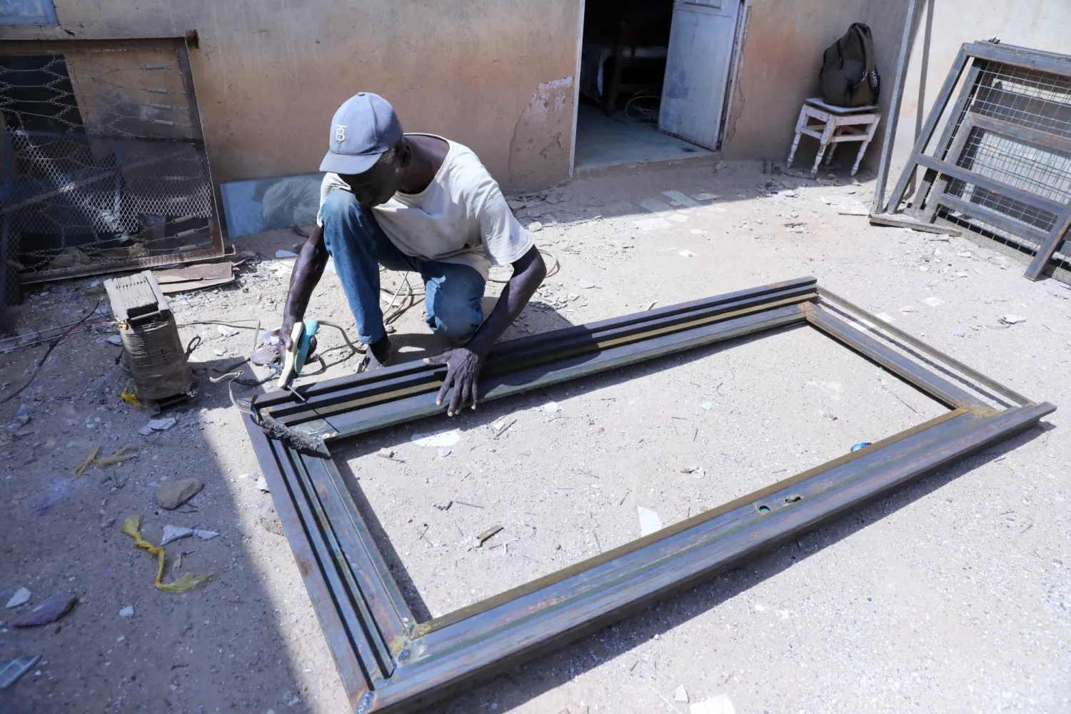 A blacksmith attempts to operate a welding machine at his workshop in Omdurman, Sudan, August 20, 2026. (Reuters)