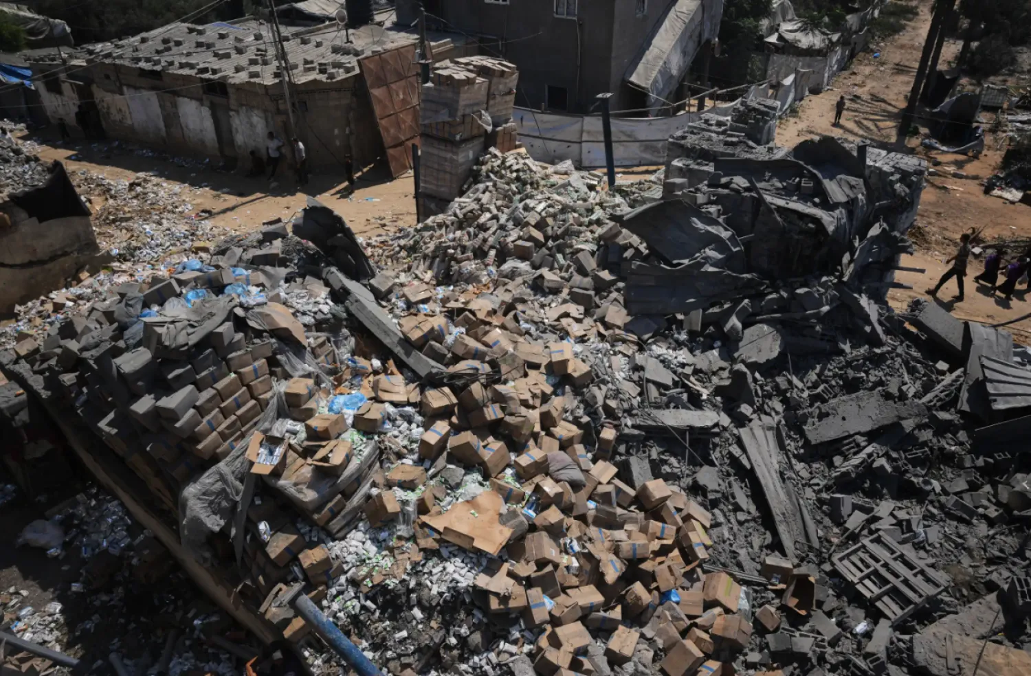 Palestinians walk past a food-aid warehouse damaged in an Israeli airstrike that targeted a nearby house in Deir al-Balah, central Gaza Strip, Wednesday, Aug. 26, 2026. (AP Photo/Abdel Kareem Hana)