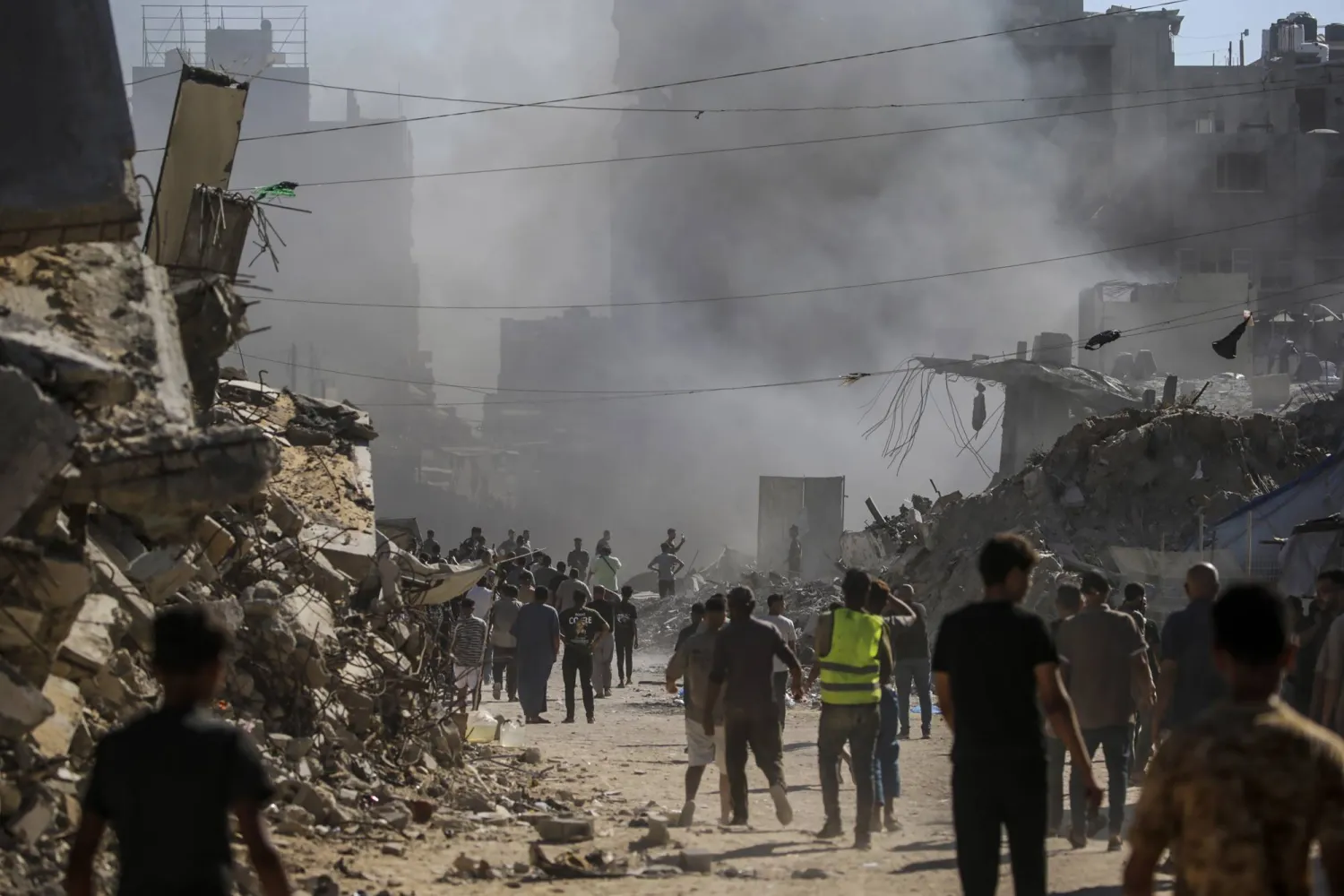 فلسطينيون يتفقدون الأضرار الناجمة عن غارة جوية إسرائيلية على حي الشيخ رضوان شمال غربي مدينة غزة (إ.ب.أ)