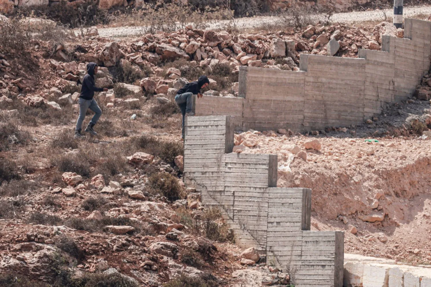 مستوطنون إسرائيليون بالقرب من منزل فلسطيني في قرية قصرة بالضفة الغربية (أ.ف.ب)