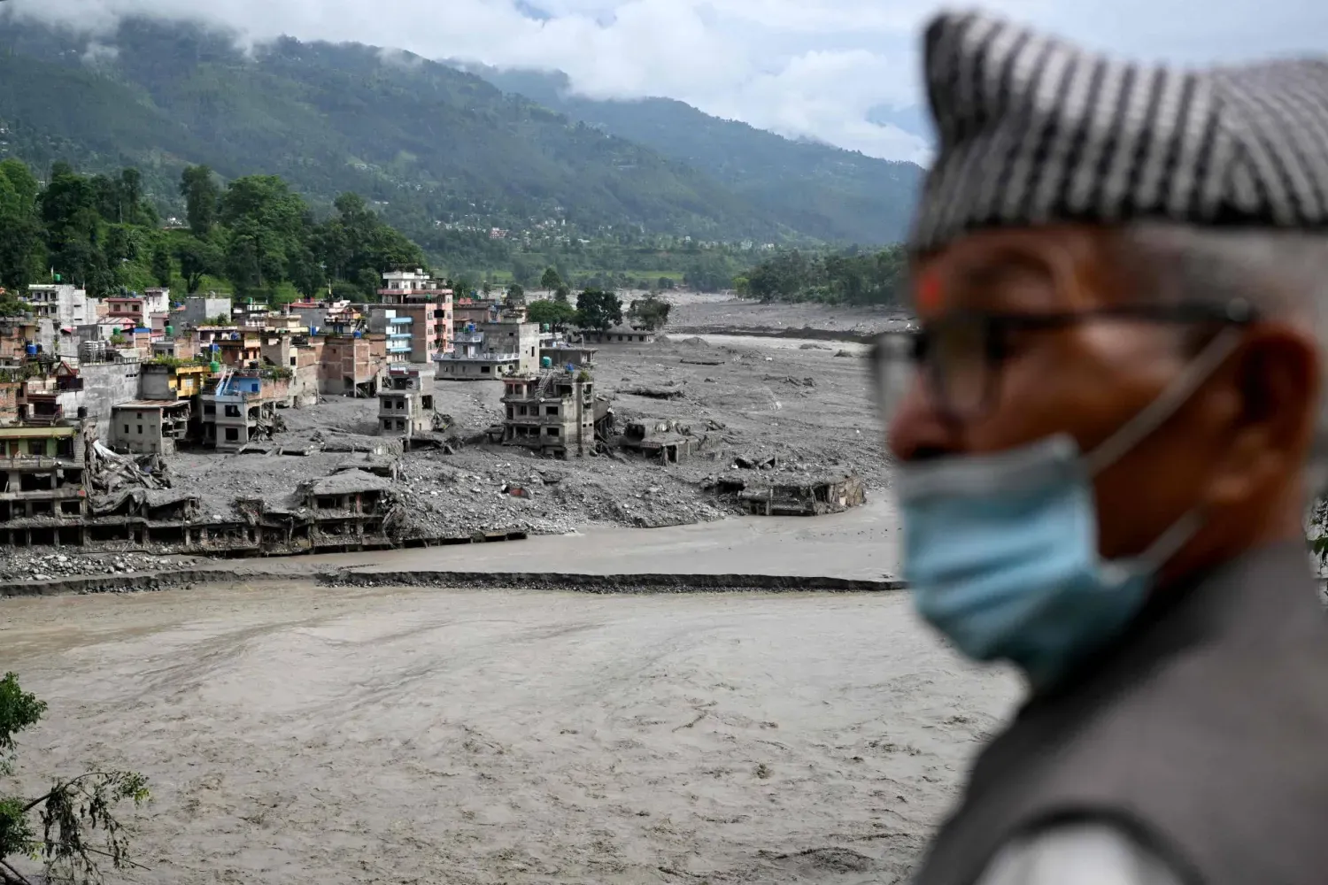 Nepal’in Nuwakot bölgesine bağlı Trishuli merkezinde ani sellerin zarar verdiği evleri inceleyen bir kişi, (AFP)