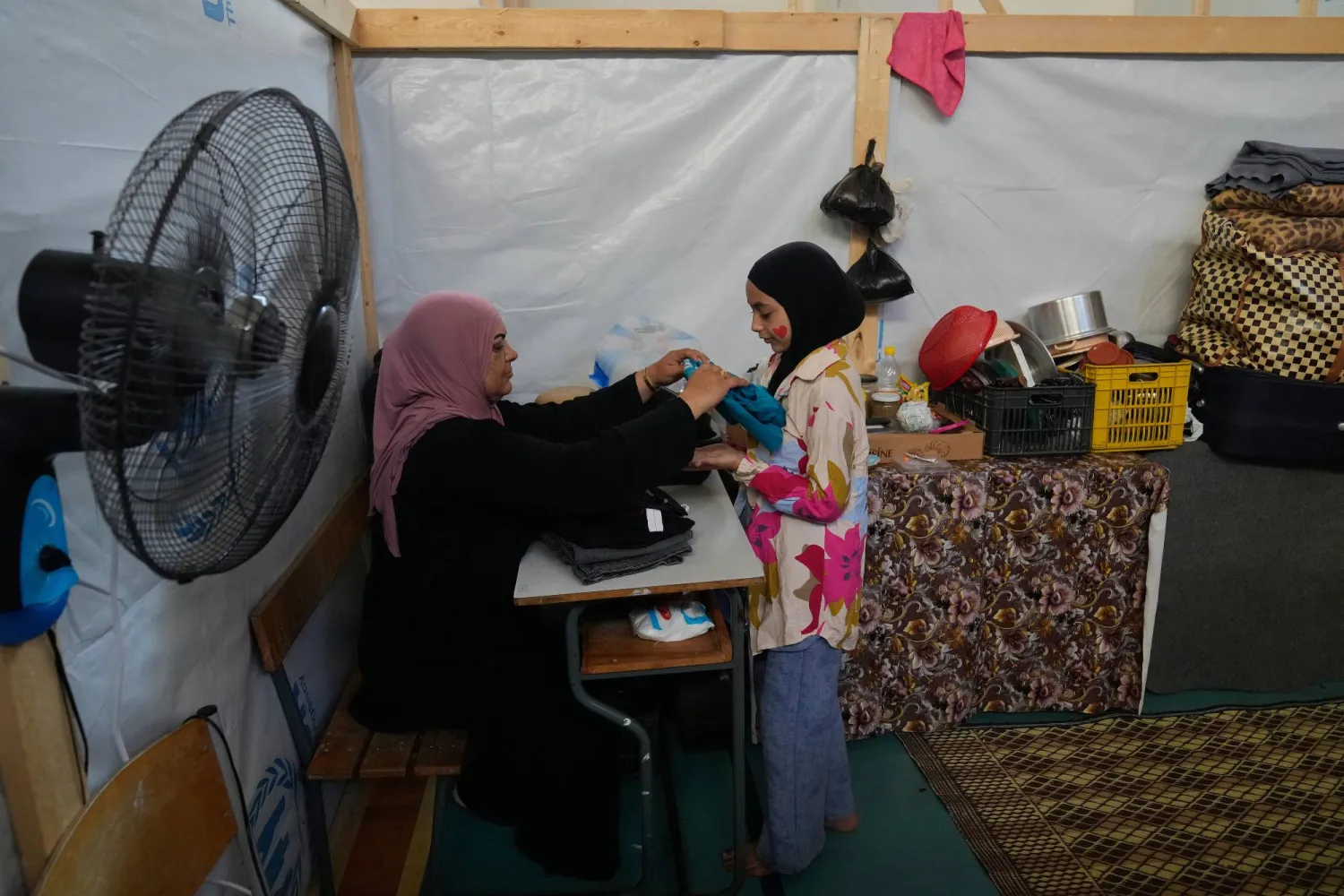 Displaced woman, Randa al-Taki, 51, and her daughter Fatima Haidar, 11, arrange their clothes inside their makeshift room that set on a basketball court inside a public school turned into a shelter for people whose villages in southern Lebanon were destroyed or occupied by Israeli forces, in Tyre, southern Lebanon, Thursday, Aug. 27, 2026. (AP)