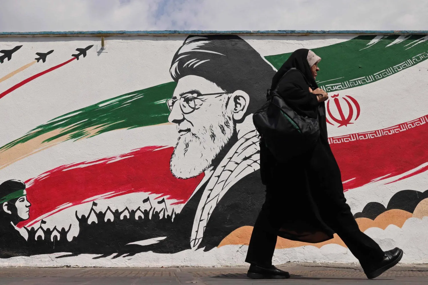 A woman walks past a wall mural of Iran's slain supreme leader Ali Khamenei, along a street in downtown of Tehran on August 31, 2026. (AFP)