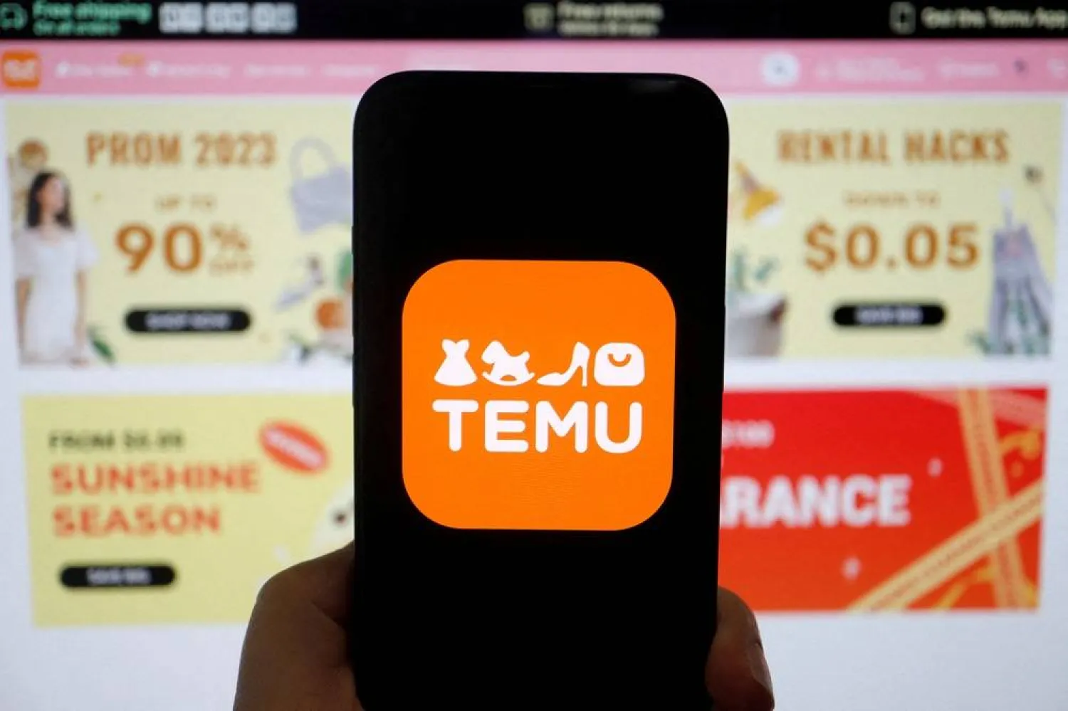 The logo of Temu, an e-commerce platform owned by PDD Holdings, is seen on a mobile phone displayed in front of its website, in this illustration picture taken April 26, 2023. (Reuters)