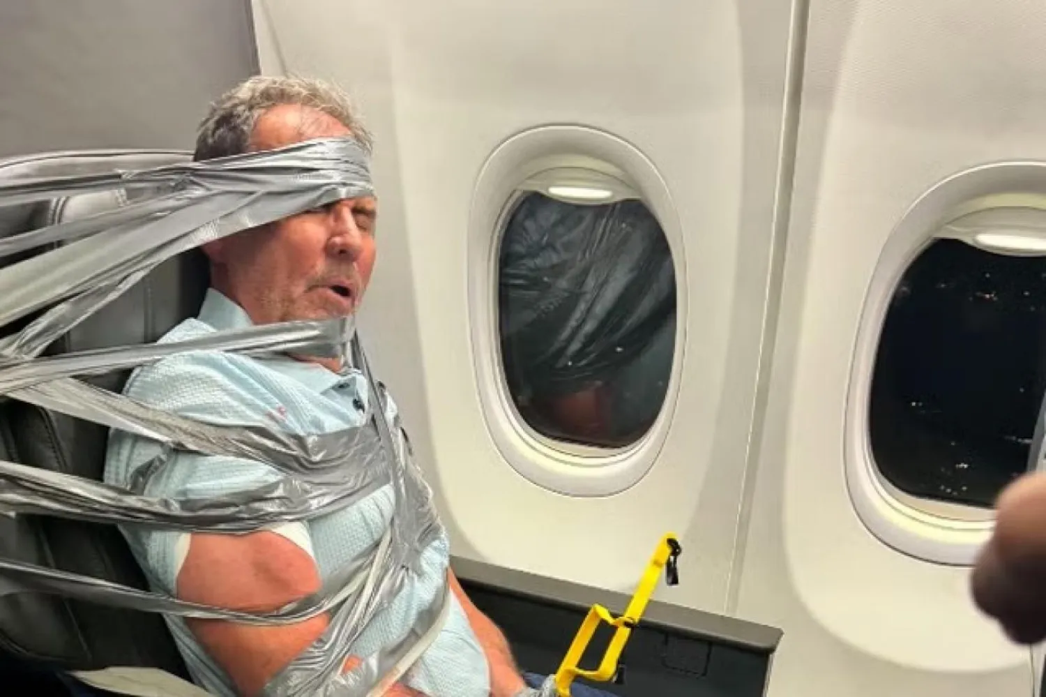 Layne Lundeen, yanındaki koltukta oturan yolcuya saldırdığı iddiasının ardından American Airlines uçağındaki koltuğuna koli bandıyla bağlanmış halde (Instagram/Richard Olenick)