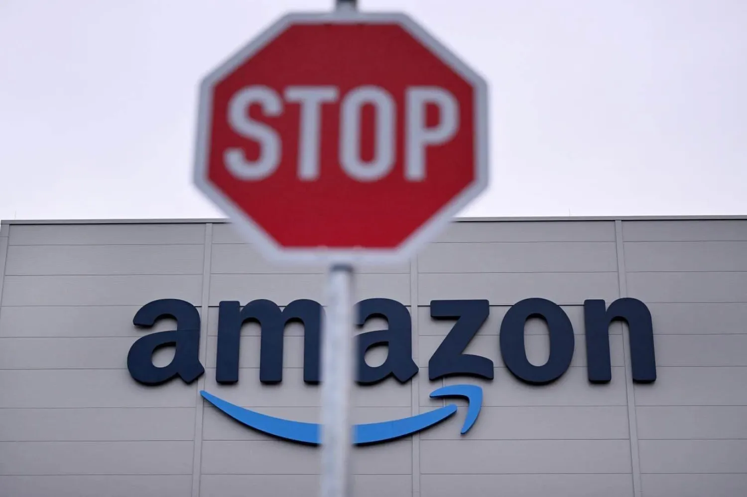 9 Aralık 2024'te Almanya'nın batısındaki Horn-Bad Meinberg'de, çevrimiçi perakende devi Amazon'un bir dağıtım merkezinin önünde "Dur" yazılı trafik tabelası görülüyor (AFP)