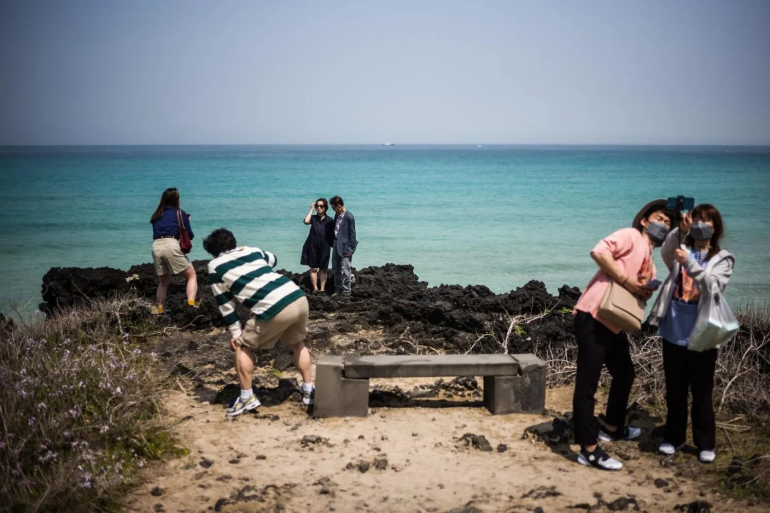 Güney Kore'nin en büyük adası Jeju'daki Jeju Şehri'nde, Hamdeok Plajı yakınında fotoğraf çeken ziyaretçiler (Arşiv/AFP)
