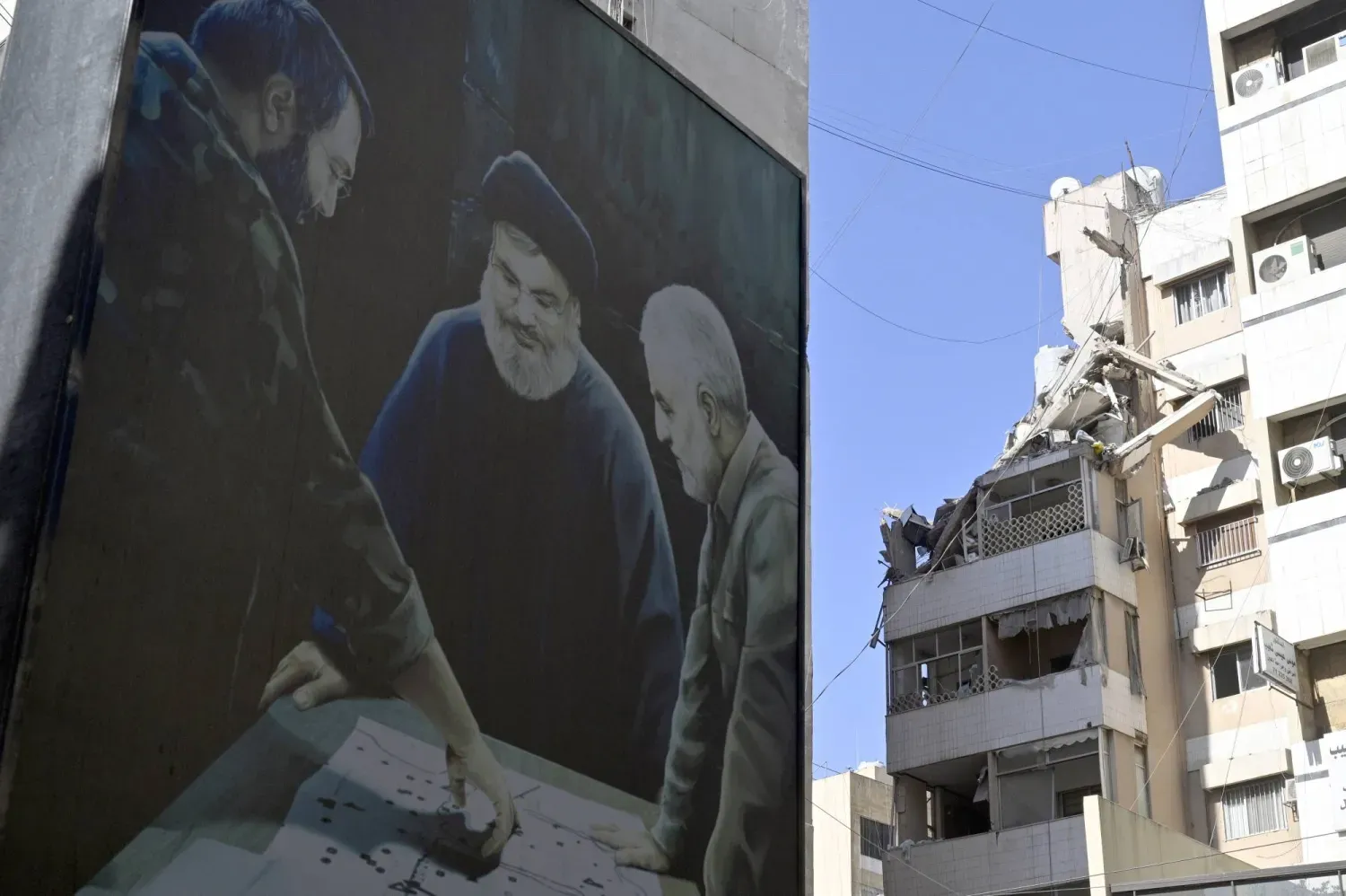 Beyrut’un güney banliyölerinde, Haret Hreik’te İsrail hava saldırısının gerçekleştiği yere yakın bir binada asılı bir pankartta Kasım Süleymani, Hasan Nasrallah ve İmad Muğniye’nin fotoğrafları görülüyor. (Arşiv – EPA)
