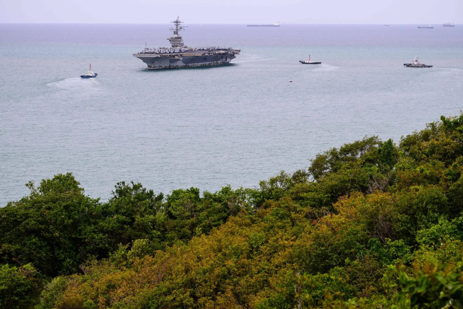 Tugboats prepare to guide US nuclear-powered aircraft carrier USS Abraham Lincoln (CVN-72) (C) towards Laem Chabang Port, near the city of Pattaya on September 2, 2026. (AFP)