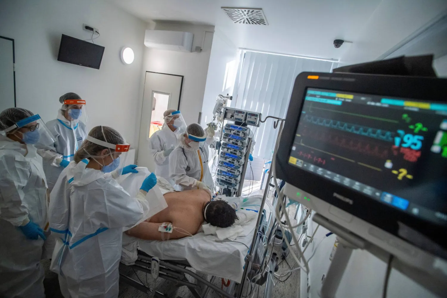 أطباء وممرضات يرتدون معدات الوقاية الشخصية يقومون برعاية مريض على جهاز التنفس الصناعي بوحدة العناية المركزة بمستشفى سانت لازلو الذي يعالج مرضى كورونا في بودابست 13 ديسمبر 2021 (أ.ب)