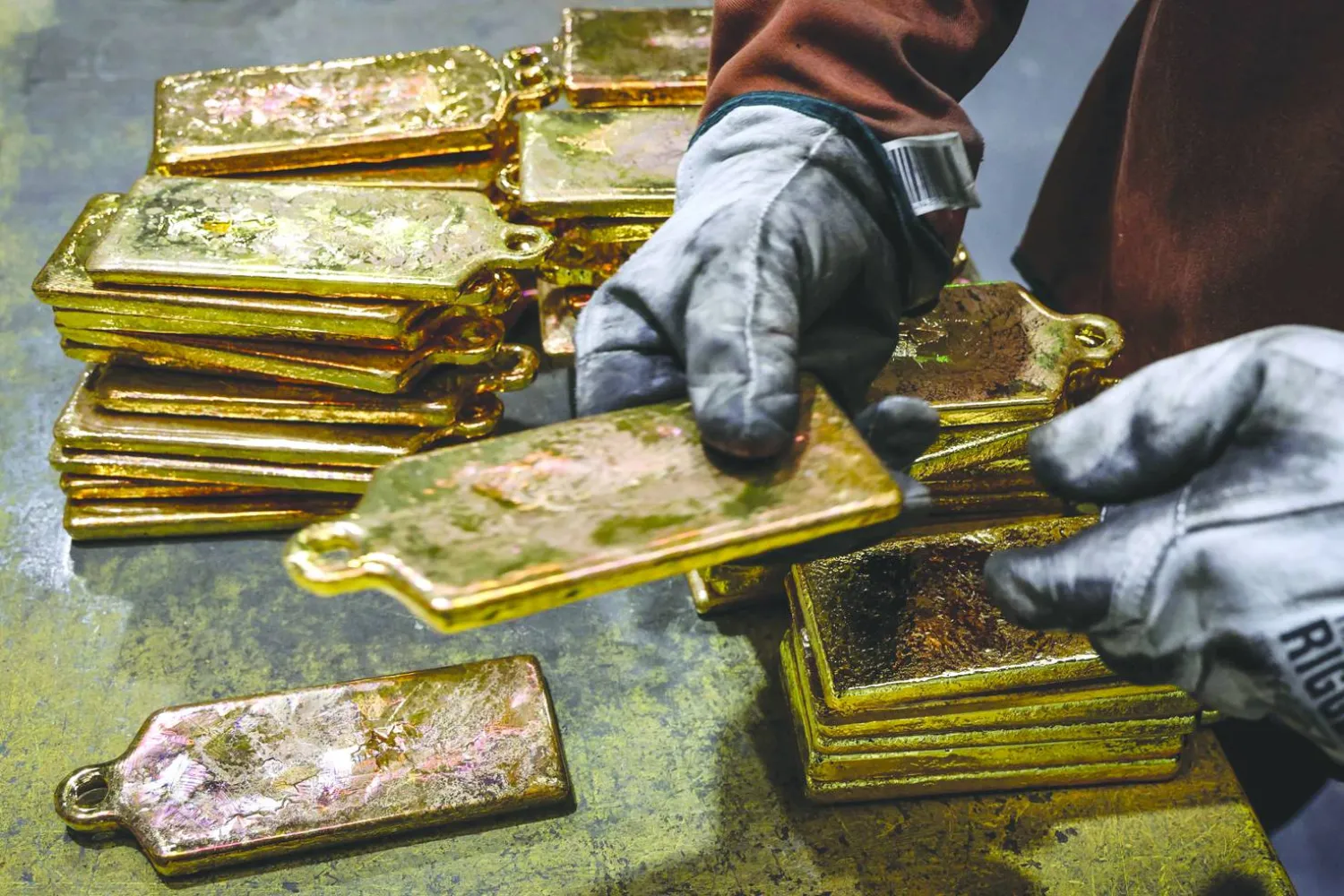 عامل مصفاة يكدّس سبائك الذهب بعد إخراجها من قوالبها في مصهر مصفاة بسيدني (أ.ف.ب)