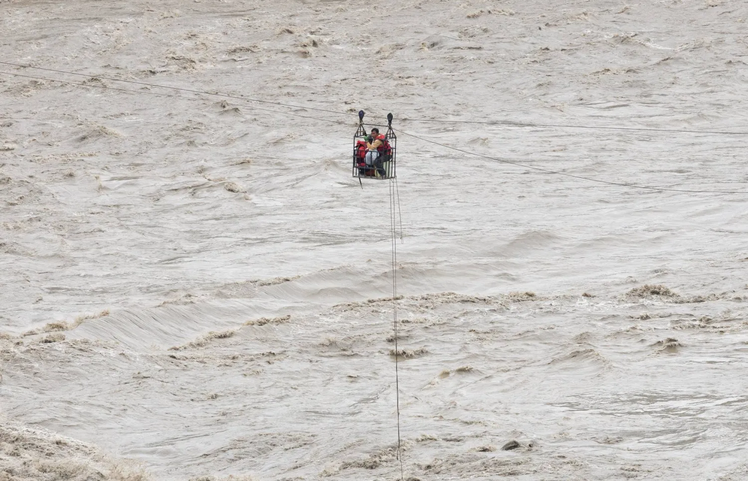 People hold onto a cage on a makeshift zip line as they cross the Trishuli River from Koloni following deadly flash floods that damaged bridges and temporarily stranded residents, in Nuwakot district, Nepal, September 4, 2026. REUTERS/Adnan Abidi