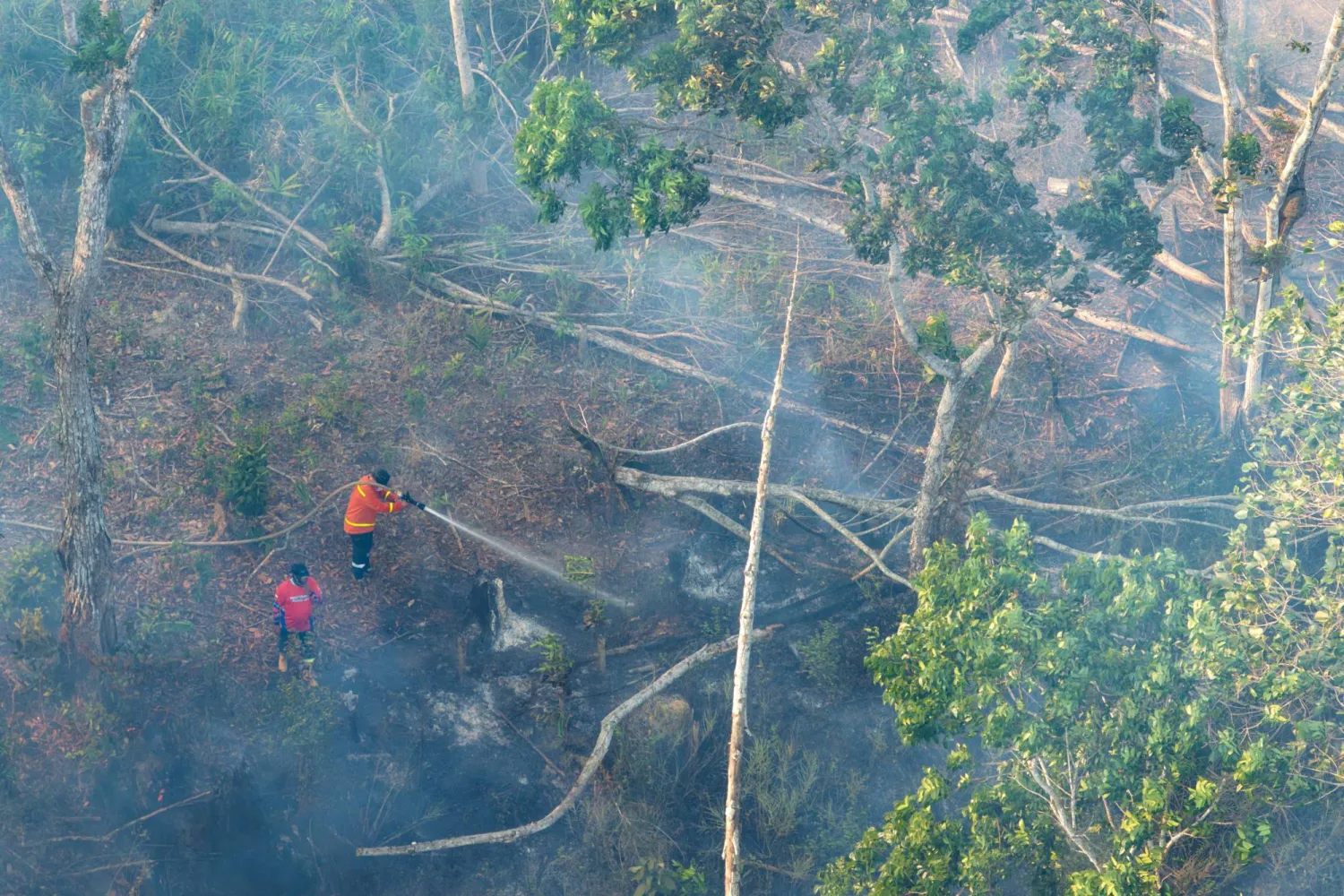 A drone view shows firefighters spraying water in an attempt to extinguish a wildfire in Soeharto Hill Forest Park, North Penajam Paser in East Kalimantan province, Indonesia, September 3, 2026. (Public Relations Office of the Nusantara Capital City Authority/Handout via Reuters) 