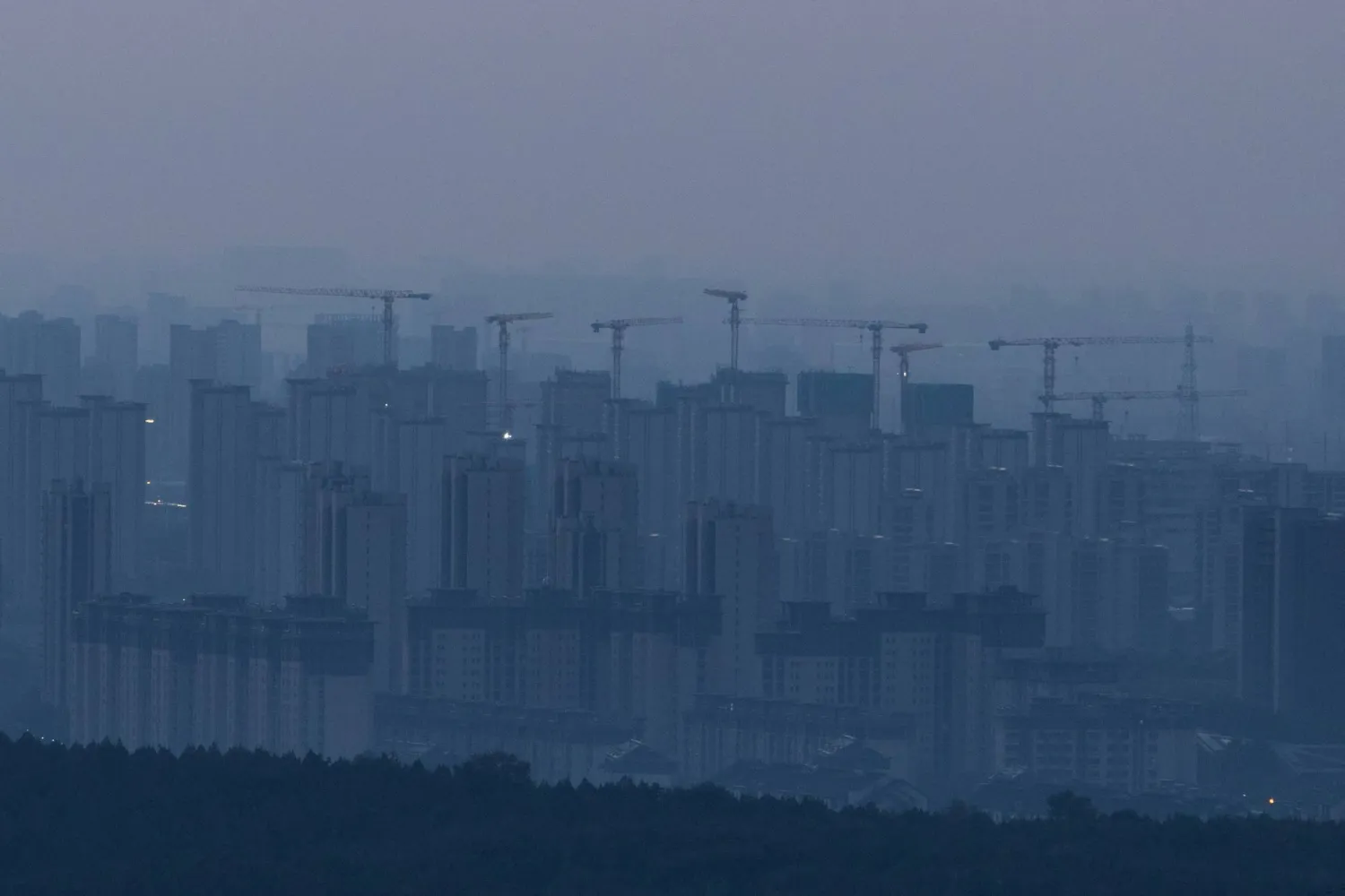 Construction cranes rise above a newly built residential district before sunrise, in Beijing, China, September 3, 2026. REUTERS/Maxim Shemetov