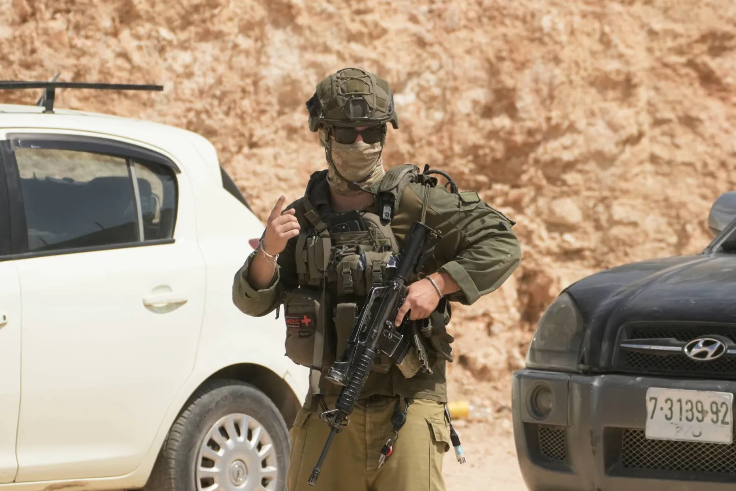 جندي إسرائيلي خلال هجوم مستوطنين على أملاك فلسطينيين في بلدة قصرة بالضفة الغربية يوم السبت (أ.ب)