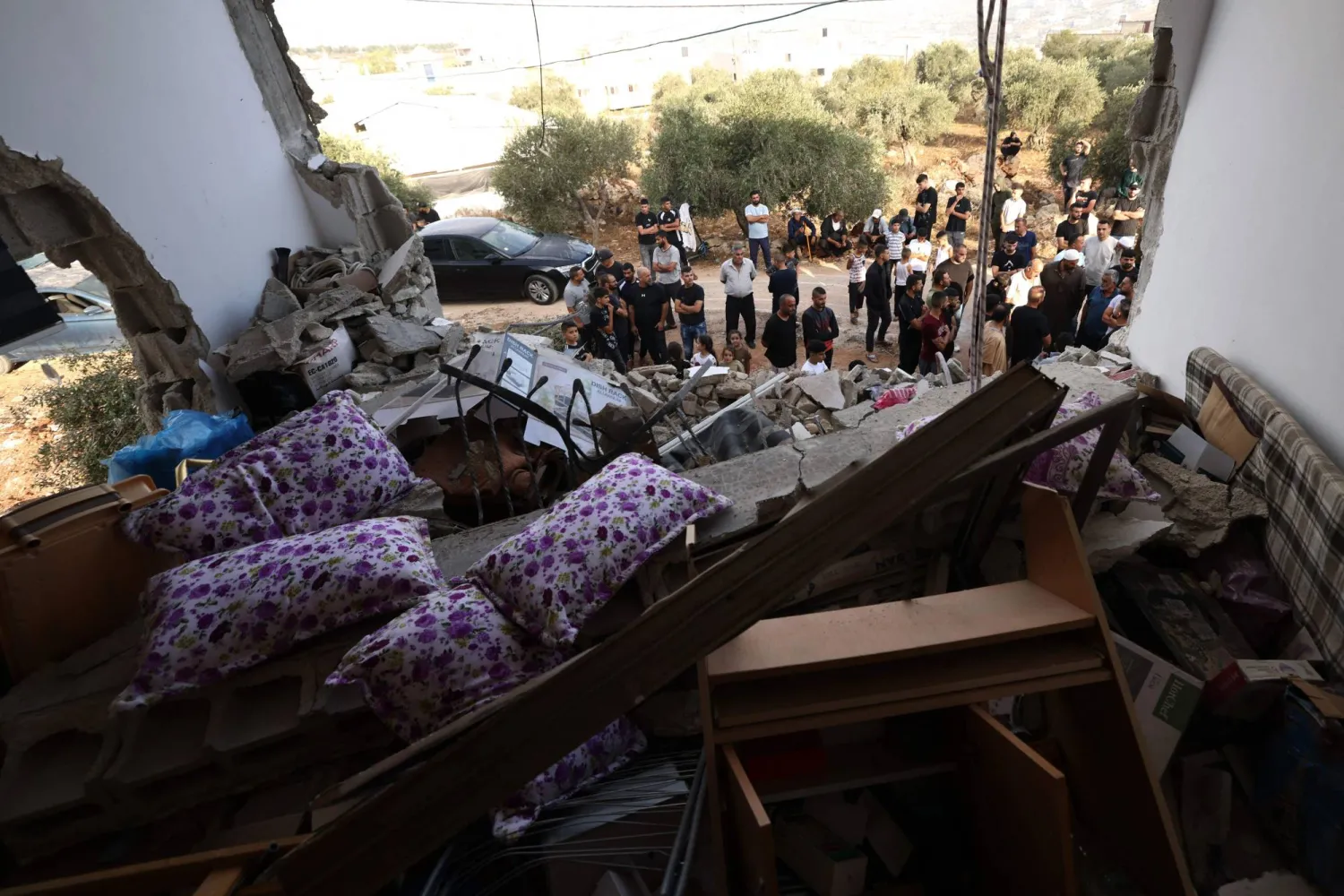 تفقد فلسطينيون منزلاً عائلياً دمره الجيش الإسرائيلي عقب عملية عسكرية بعد أن تحصن رجل فلسطيني داخل المنزل في قرية عقربة بالضفة الغربية المحتلة - جنوب مدينة نابلس (أ.ف.ب)
