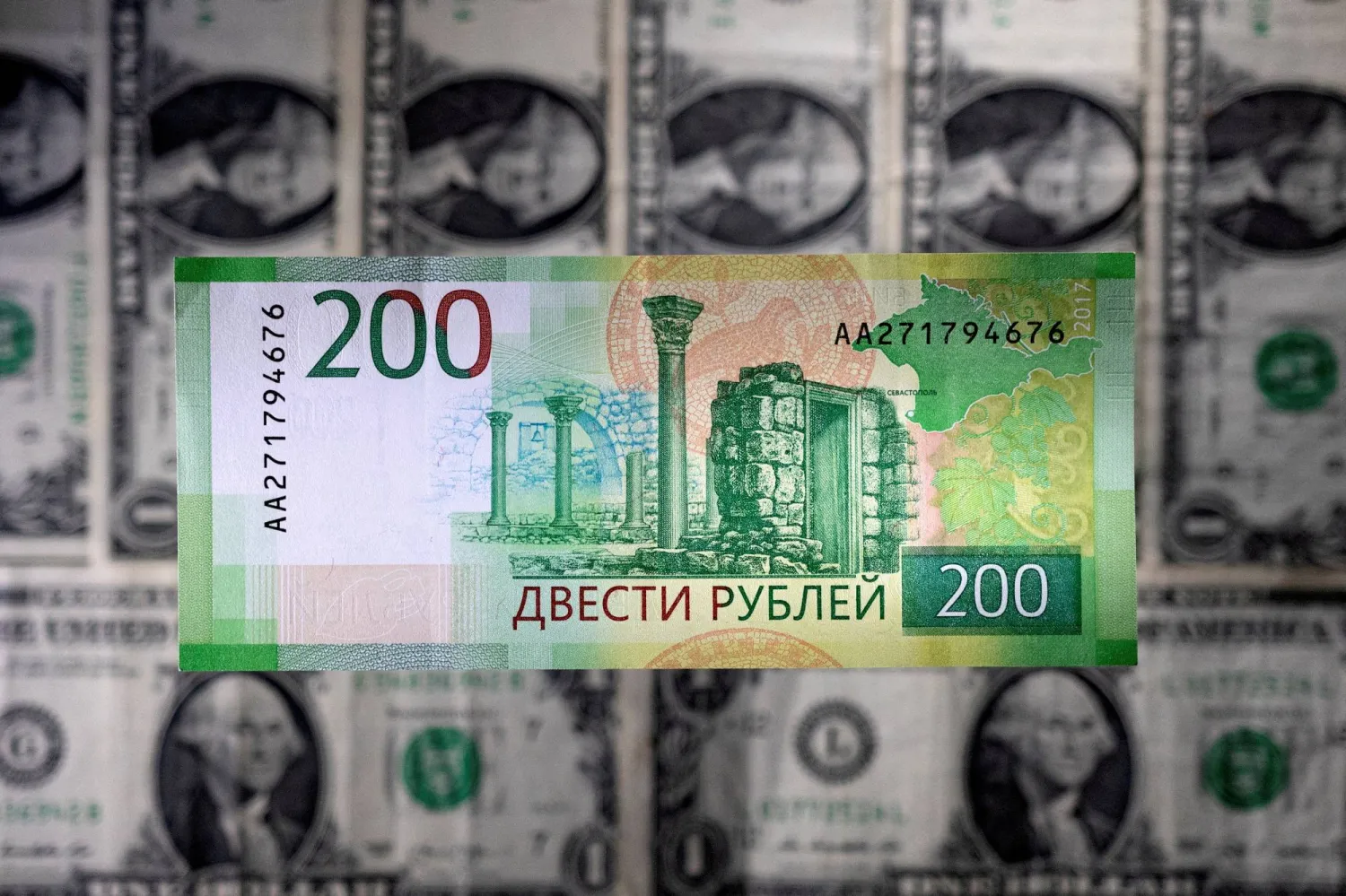 ورقة نقدية من الروبل الروسي موضوعة فوق أوراق نقدية من الدولار الأميركي (رويترز)
