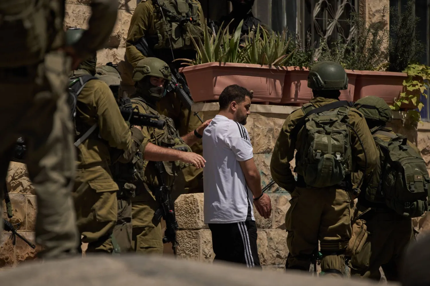 عناصر من القوات الإسرائيلية تعتقل فلسطينياً في أحد شوارع بلدة عناتا بالضفة الغربية المحتلة الثلاثاء (أ.ب)