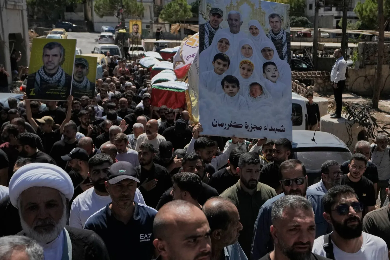 Mourners carry pictures of victims killed in an Israeli airstrike on Kafr Rumman in southern Lebanon during their funeral. (AP) 