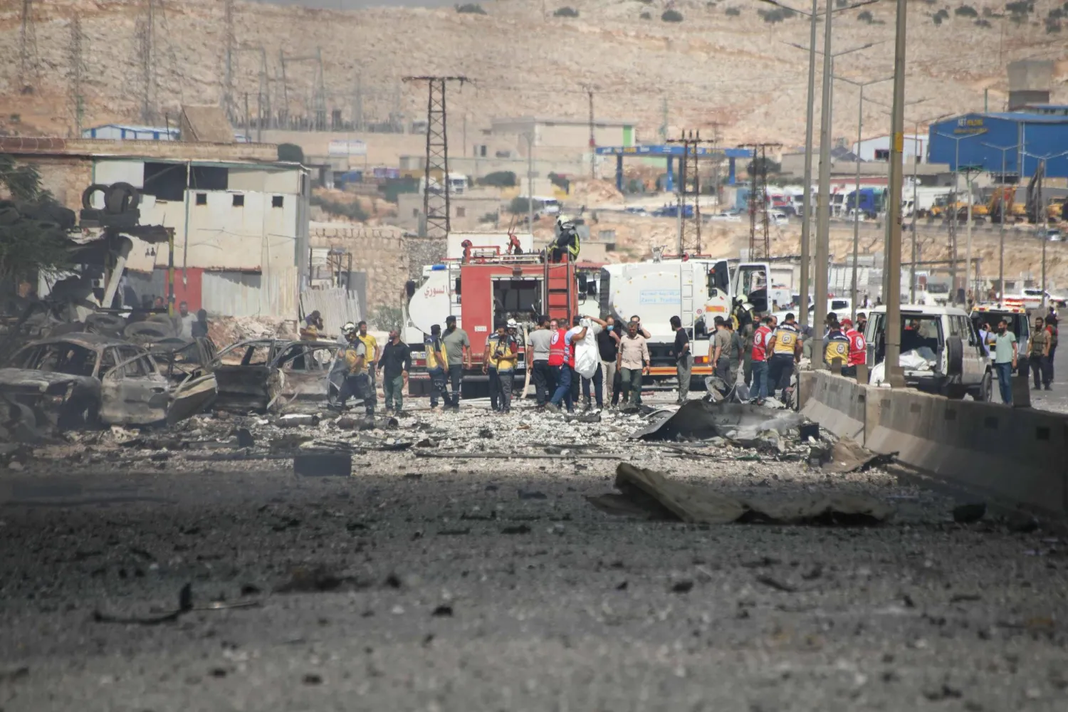 رجال إنقاذ من الخوذ البيضاء السوريين يتفقدون موقع انفجار مستودع مؤقت للأسلحة والمراسم الحربية في بلدة سرمدا بمحافظة إدلب (أ.ف.ب)