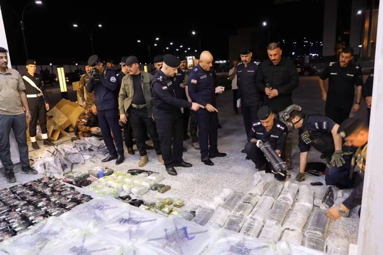 ضباط من الشرطة في الأنبار العراقية يعاينون مقذوفات ومسيرات تم ضبطها في المحافظة (إعلام أمني)