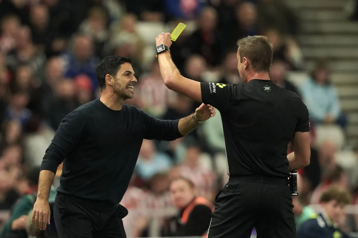  Referee John Brooks, right, shows a yellow card to Arsenal's manager Mikel Arteta during the English Premier League soccer match between Sunderland and Arsenal in Sunderland, England, Saturday, Sept. 12, 2026. (AP) 