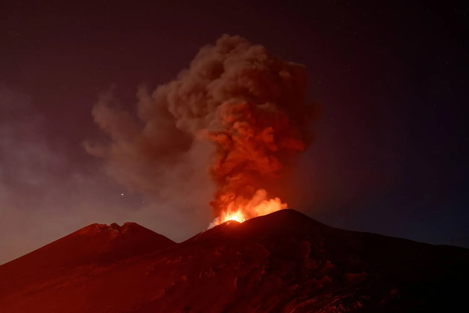 Volcanic material and fumes rise from Mount Etna during an eruption under a starry sky in Sicily, Italy, July 30, 2026. (Reuters) 