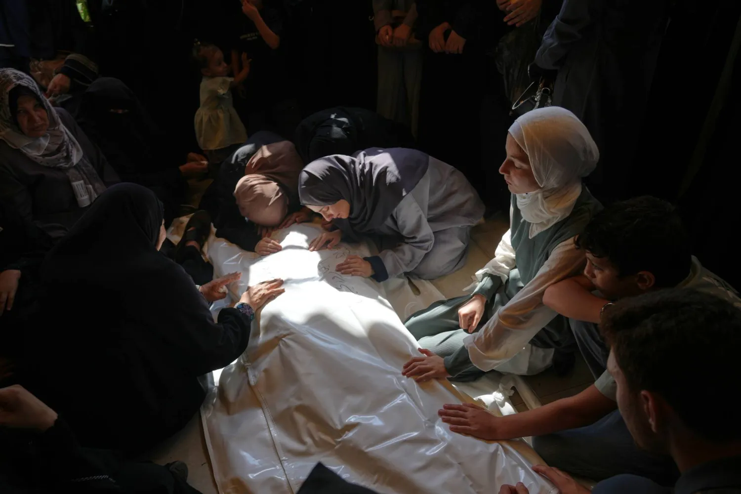 فلسطينيات يبكين محمد اليازوري الذي قُتل بغارة جوية إسرائيلية الخميس الماضي قبيل تشييع جثمانه في خان يونس جنوب غزة (أ.ب)