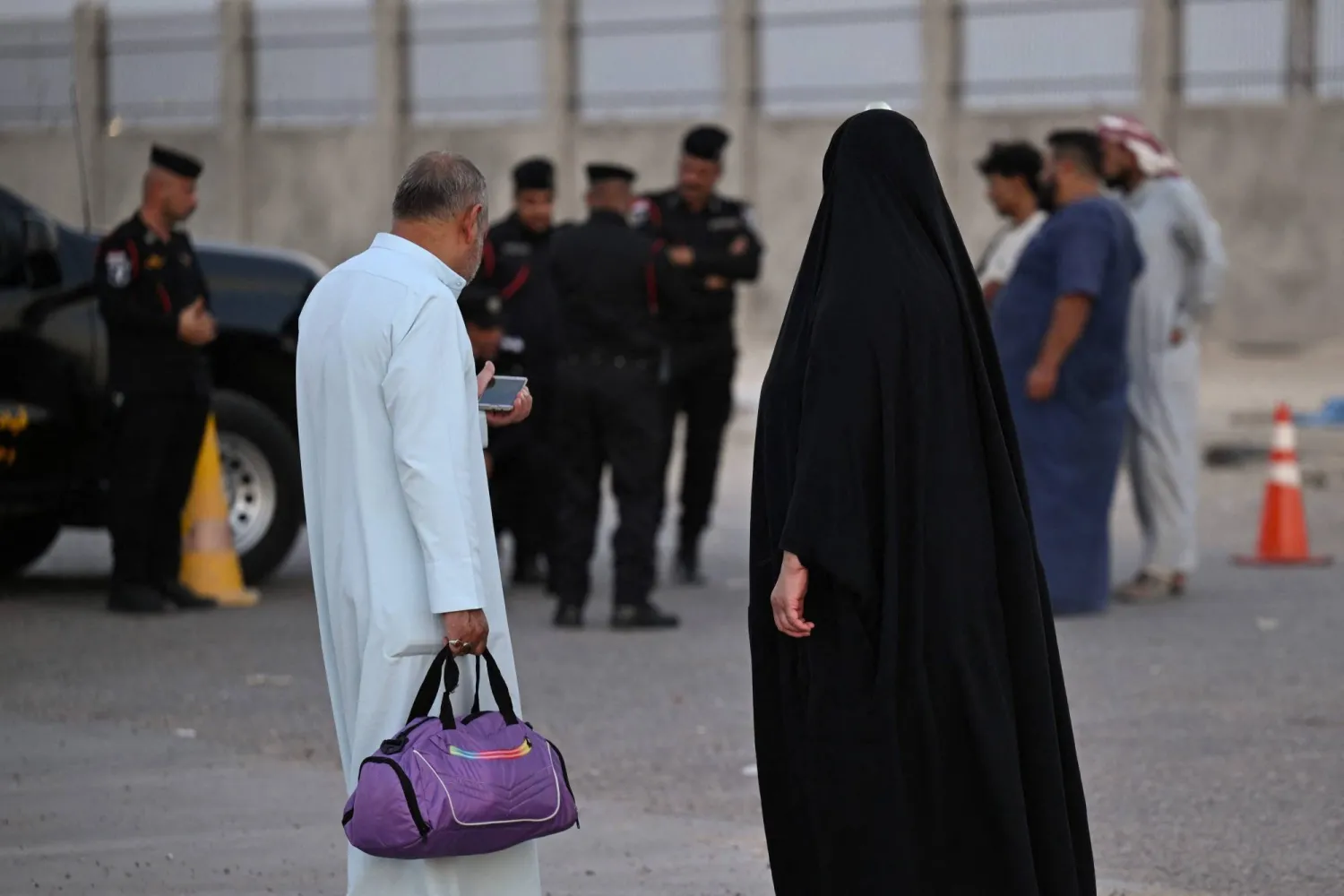 مسافرون عراقيون وإيرانيون ينتظرون عند معبر الشلامجة في البصرة يوم السبت بعدما أغلقت الحكومة العراقية المعبر الحدودي مع إيران خلال عمليات البحث عن متورطين في الاعتداء بالمسيّرات على المملكة العربية السعودية (أ.ف.ب)