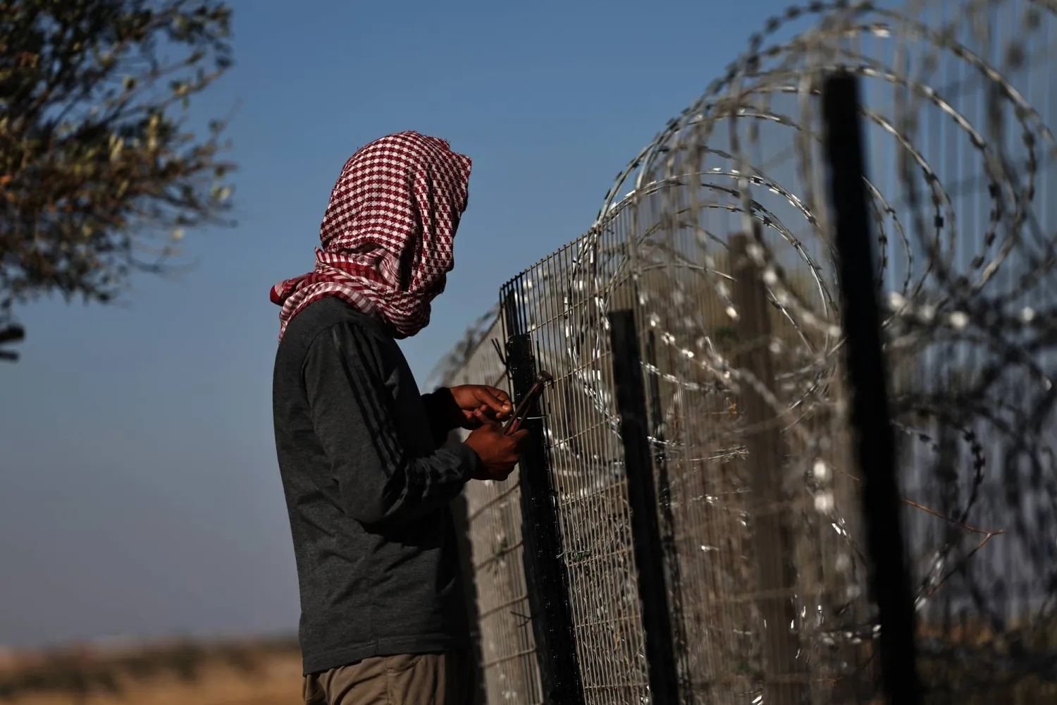 فلسطيني أمام أسلاك شائكة تحيط بمنزله لحمايته من هجمات المستوطنين في قرية الطيبة بالضفة الغربية يوم 9 سبتمبر 2026 (إ.ب.أ)
