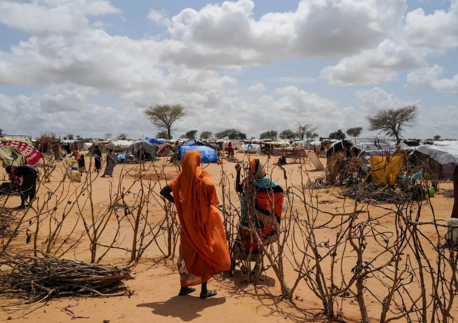 A Sudanese woman, who fled the conflict in Geneina in Sudan's Darfur region, talks to her relative through a fence next to makeshift shelters, in Adre, Chad August 5, 2023. (Reuters)