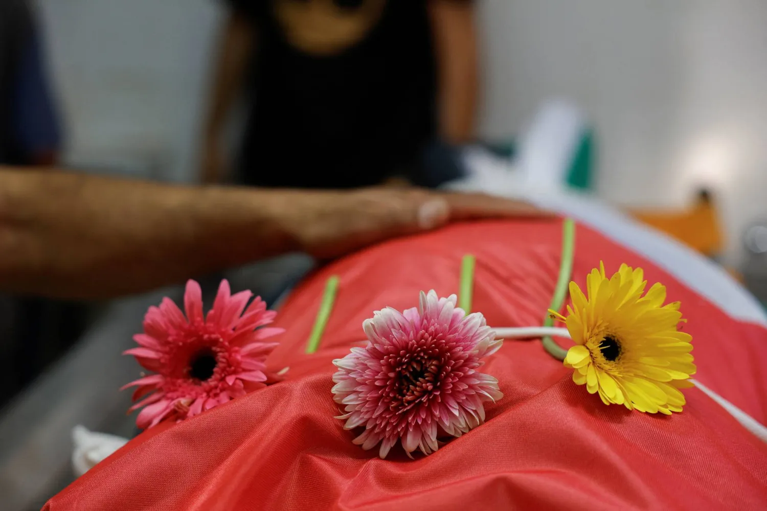 وُضعت زهور على جثمان رجل فلسطيني يبلغ من العمر 54 عاماً، قُتل على يد القوات الإسرائيلية خلال مداهمة، بينما كان المشيعون ينعونه في مستشفى بمدينة رام الله في الضفة الغربية (رويترز)