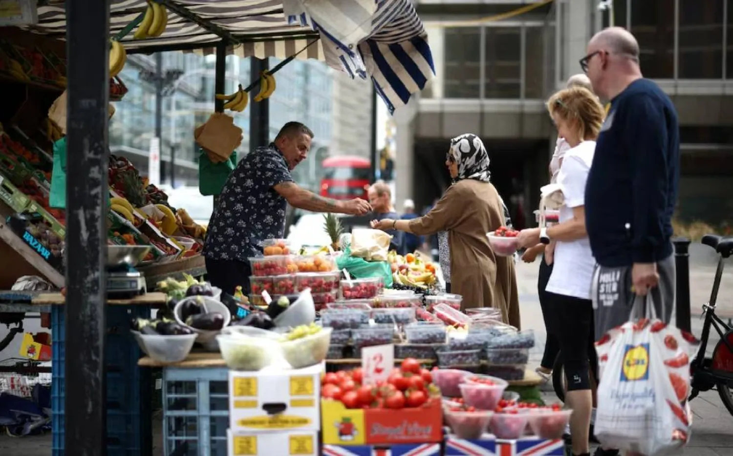 متسوِّق يشتري الفواكه والخضراوات من إحدى بسطات البيع في وسط لندن ببريطانيا (رويترز)