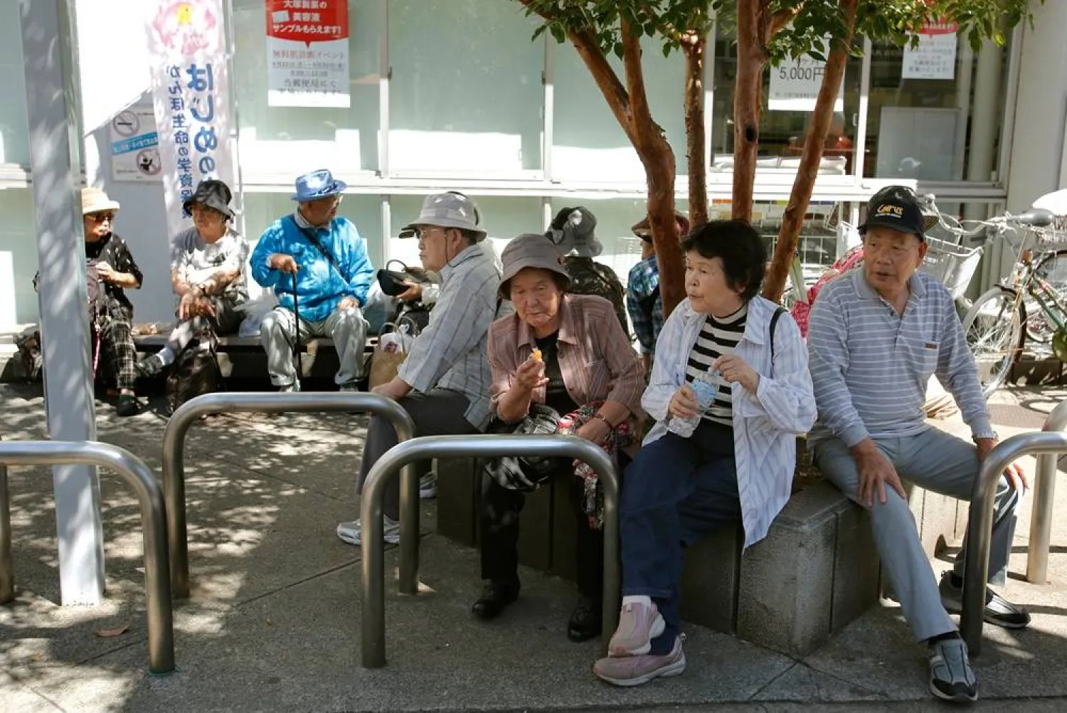 Elderly people rest under the shade of a tree in Tokyo, Sunday, Sept. 14, 2014. (AP)