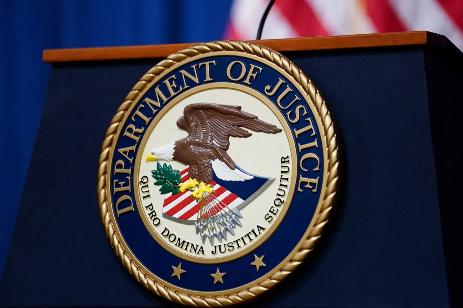 The seal of the US Justice Department is seen on the podium in the Department's headquarters briefing room in Washington, January 24, 2023. (Reuters)