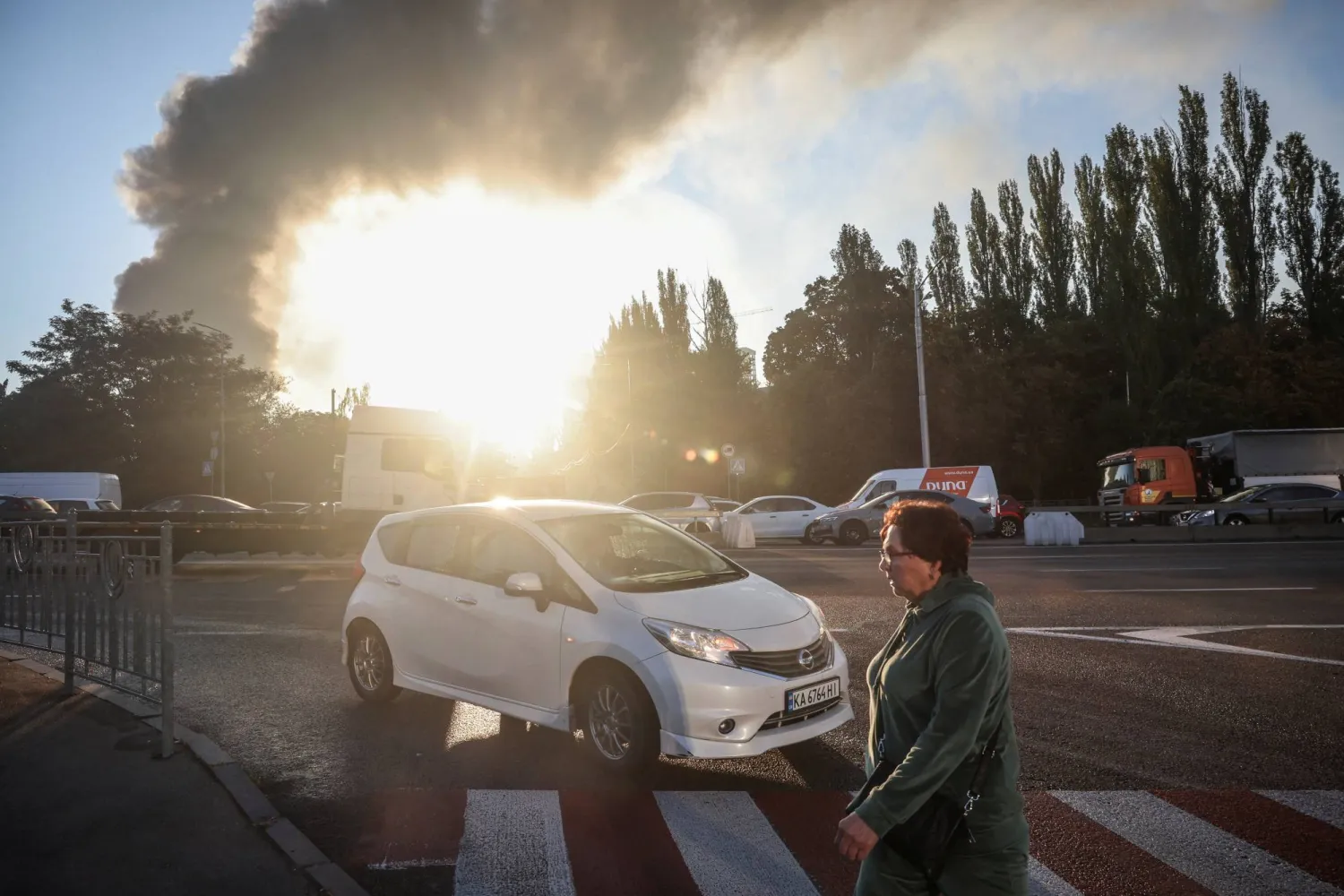  A woman crosses a road as smoke rises in the background from the site of a Russian drone strike, amid Russia’s attack on Ukraine, in Kyiv, Ukraine, September 16, 2026. (Reuters)