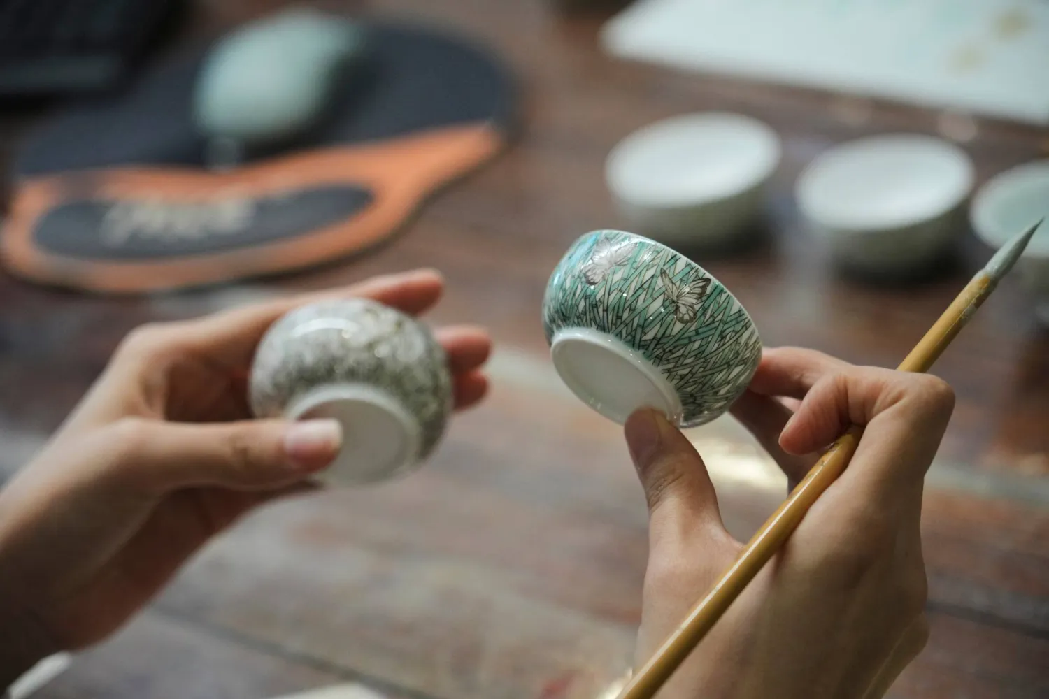 Chinese porcelain artist Chen Qing holds up two cups after painting them in Jingdezhen, known as China's "Porcelain Capital," in eastern China's Jiangxi province, Tuesday, Sept. 1, 2026. (AP Photo/Achmad Ibrahim)
