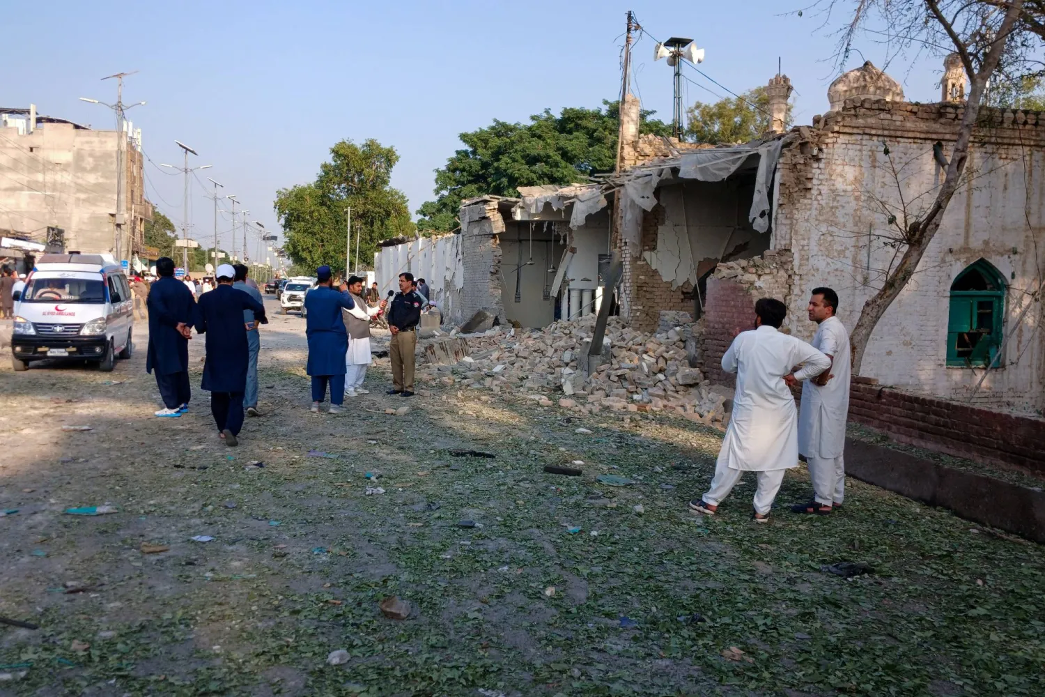 أشخاص يقفون بالقرب من سيارة إسعاف وجزء متضرر من مركز للشرطة عقب هجوم انتحاري في كوهات بباكستان يوم 18 سبتمبر 2026 (رويترز)
