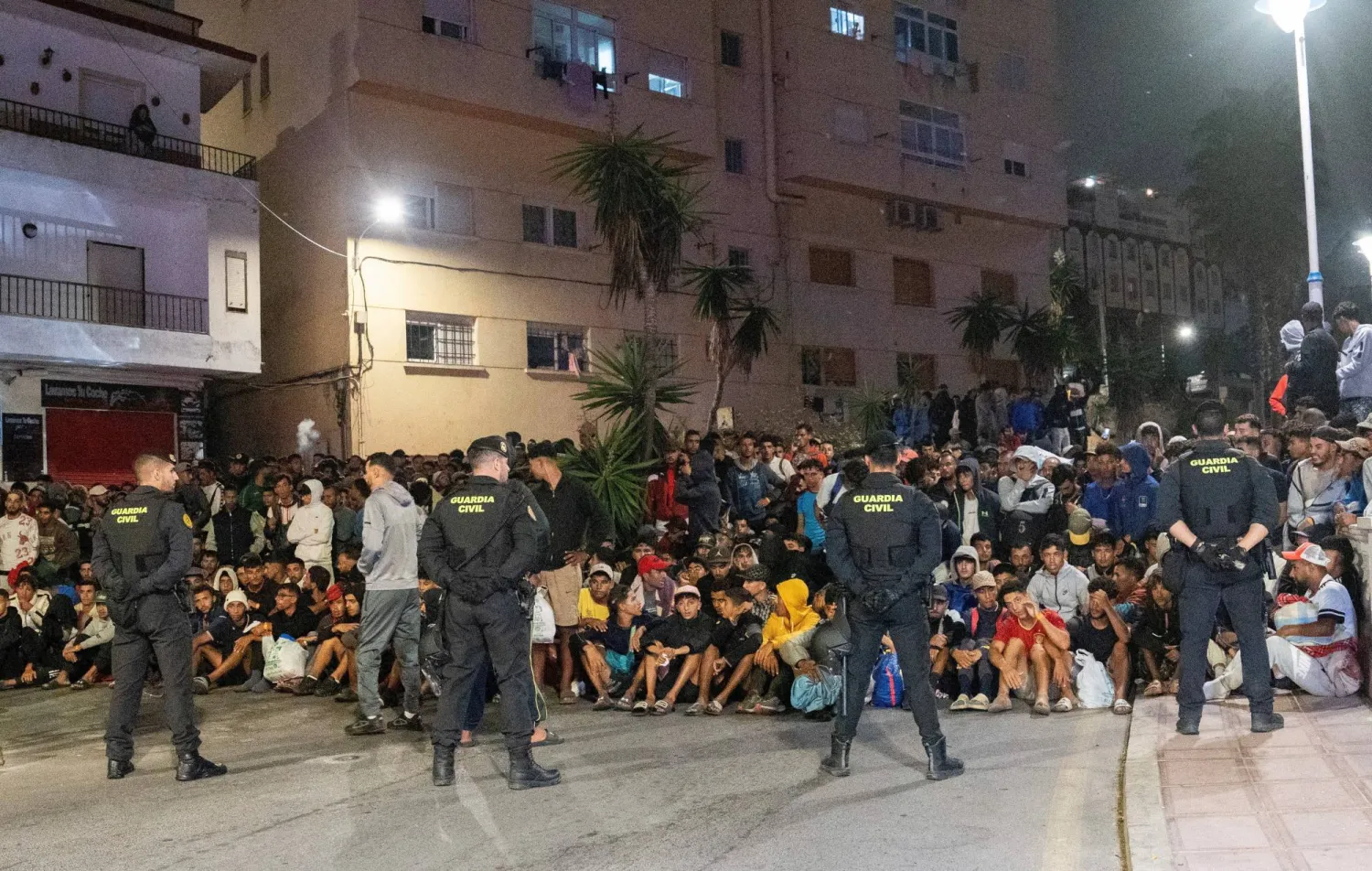 عناصر الشرطة خلال تأمين عملية نقل المهاجرين من شواطئ سبتة إلى مخيم في منطقة الميناء (رويترز)