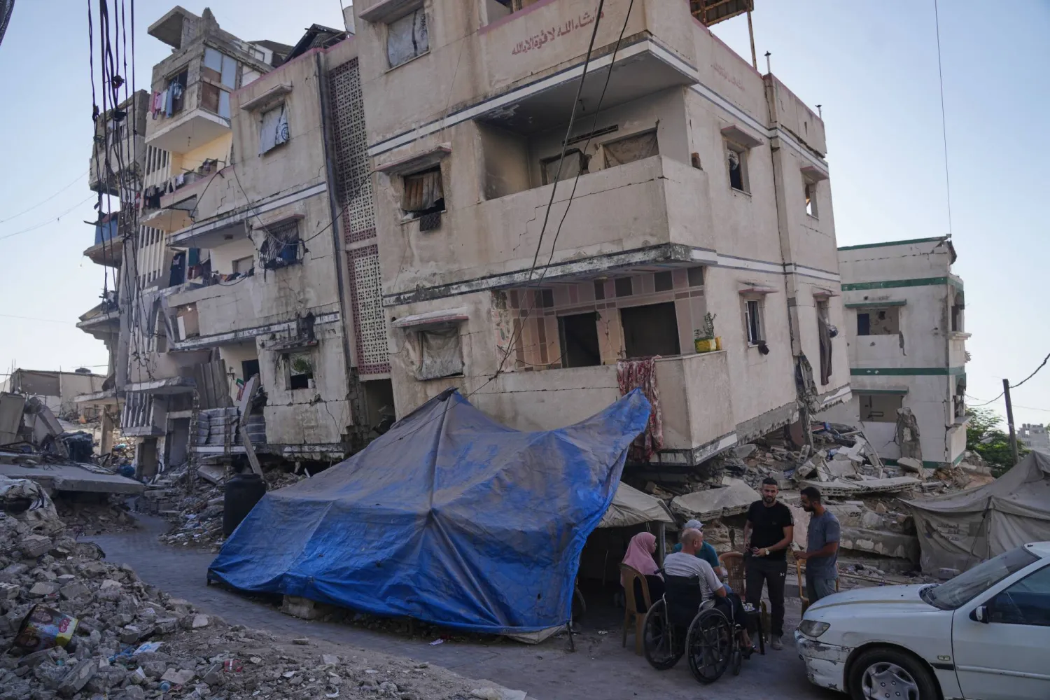 فلسطينيون اتخذوا ملجأ بجوار منزل متضرر من القصف الإسرائيلي على قطاع غزة (أ.ب)
