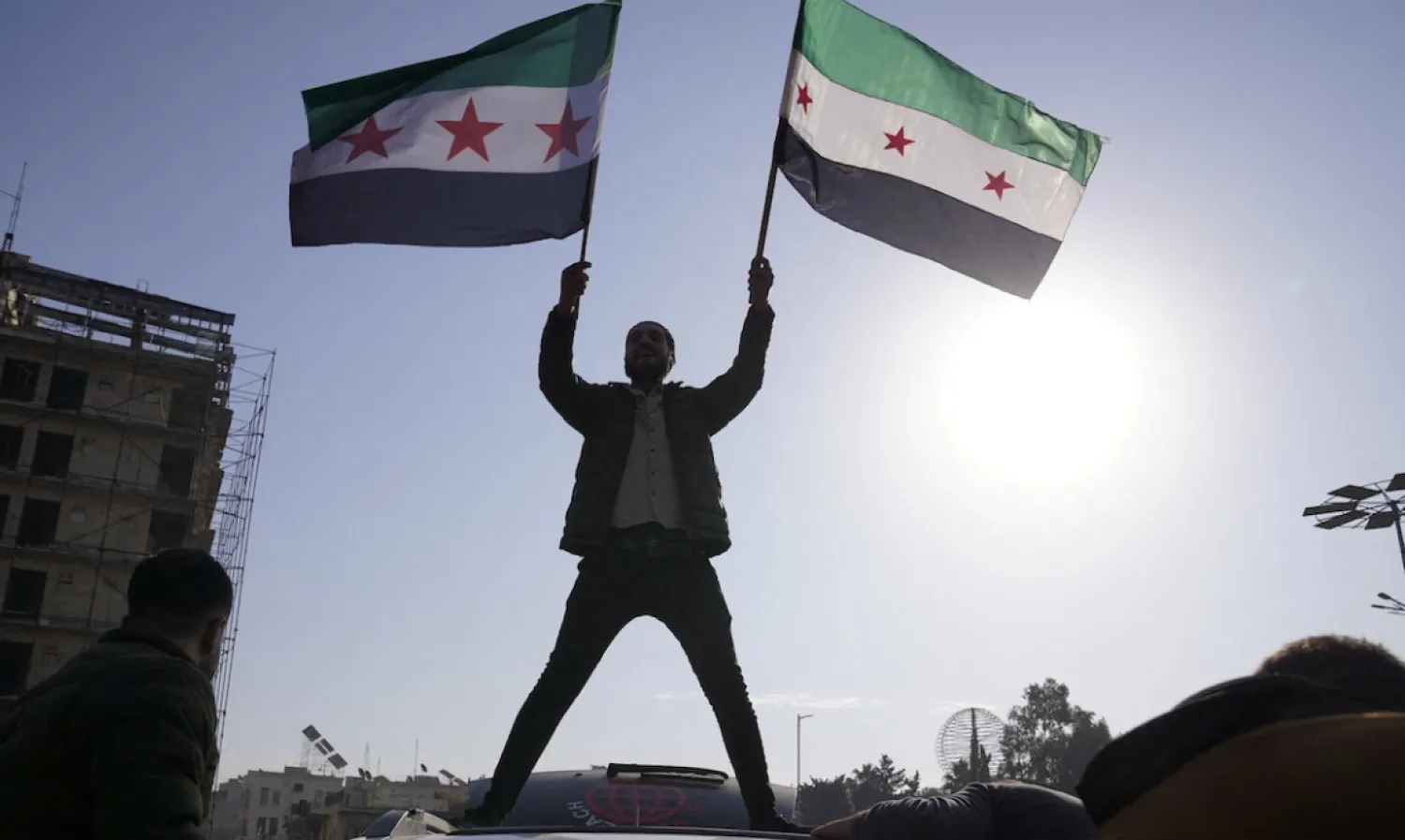 A man holds Syrian opposition flags as he celebrates after Syria's army command notified officers that President Bashar al-Assad's 24-year authoritarian rule has ended, in Aleppo, Syria December 8, 2024. REUTERS/Karam al-Masri