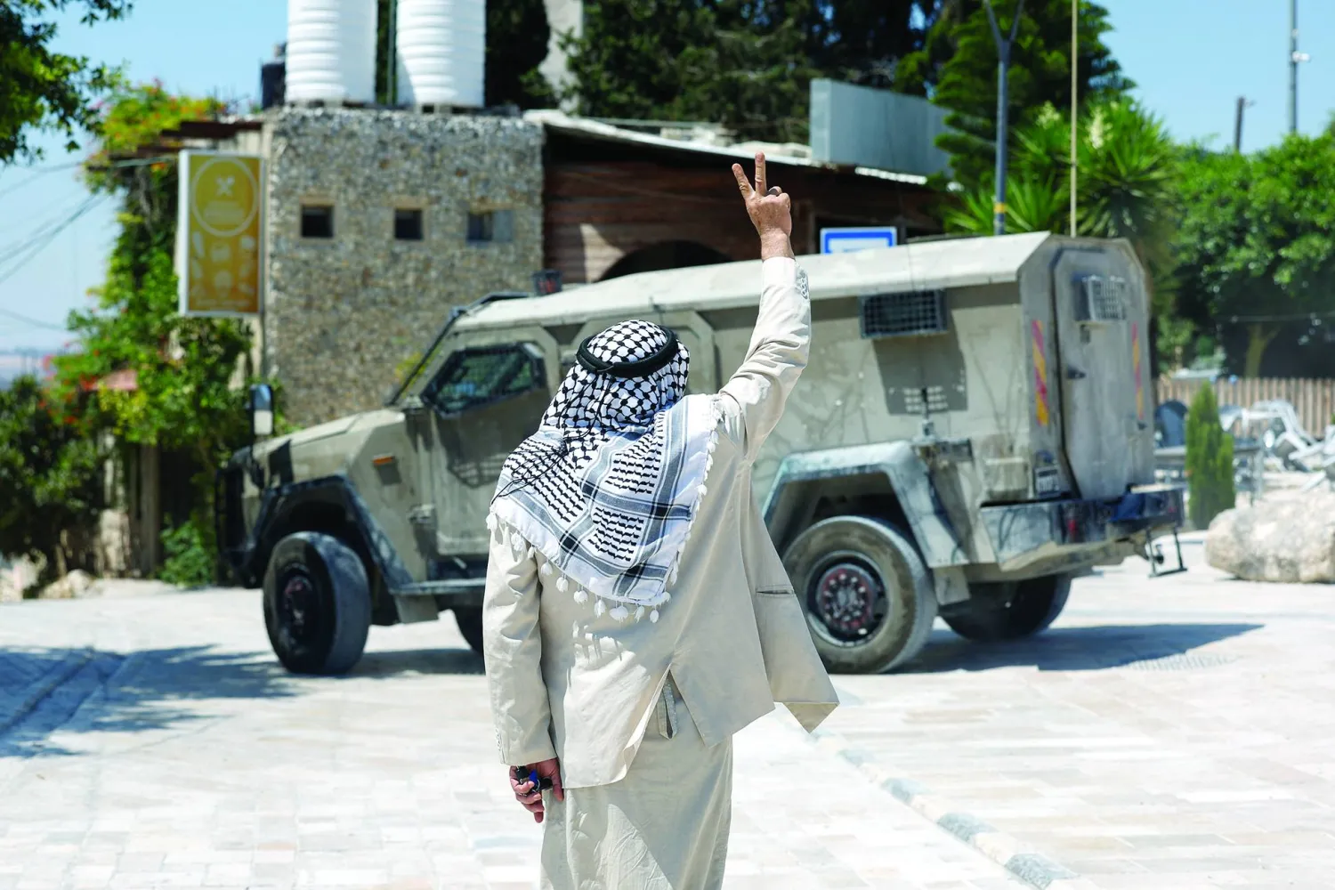 مستوطنون وجنود إسرائيليون يقفون بحقل في حين يُمنع المزارعون الفلسطينيون من قطف الزيتون بقرية سعير قرب مدينة الخليل بالضفة الغربية (أرشيفية - أ.ف.ب)