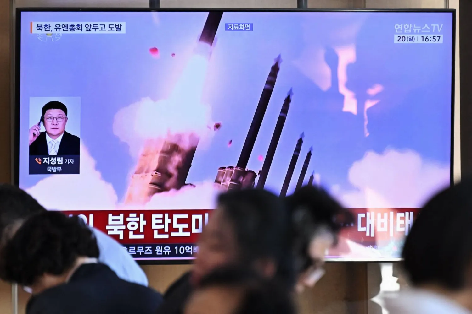 People sit near a television screen showing a news broadcast with file footage of a North Korean missile test, at a train station in Seoul on September 20, 2026. (Photo by Lillian SUWANRUMPHA / AFP)