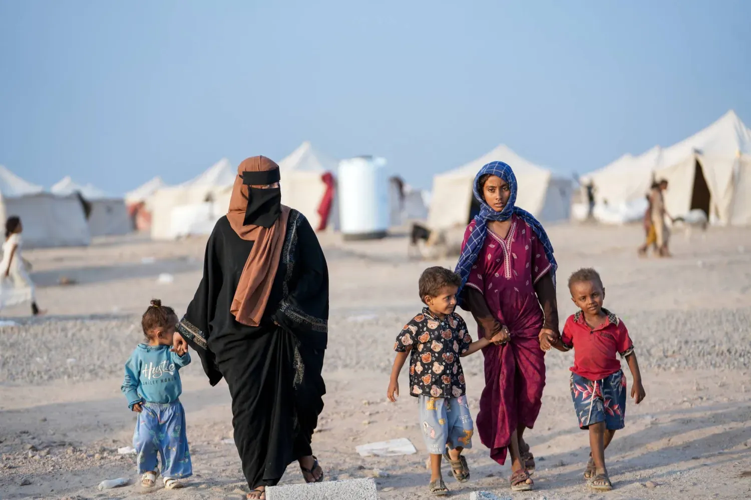 Savaş bölgelerinden kaçan yerinden edilmiş kişiler, dün Aden yakınlarındaki bir yerinden edilmişler kampında yürürken. (Reuters)