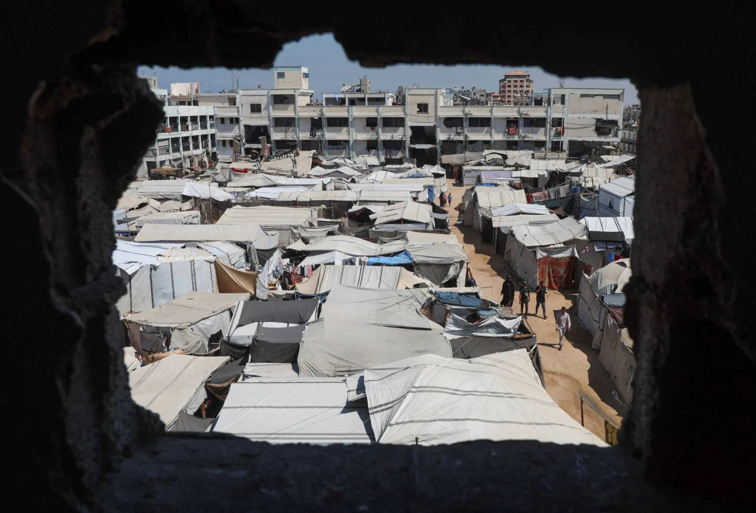  Displaced Palestinians walk through a tent camp inside a school-turned-shelter in Khan Younis, in the southern Gaza Strip, September 10, 2026. (Reuters)